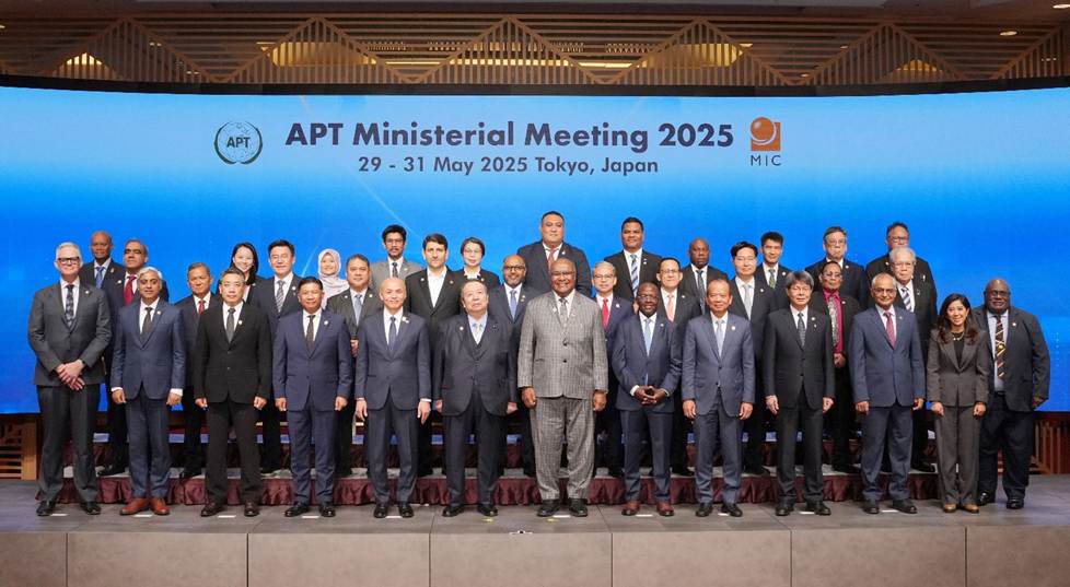 A group of men in suits standing in front of a large screen

Description automatically generated